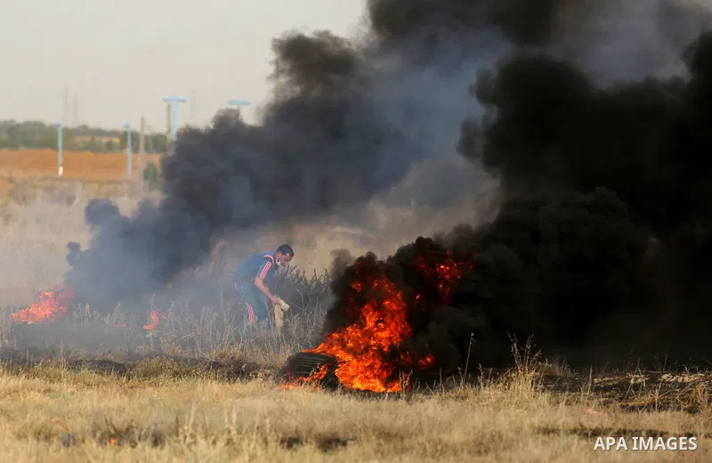 A Palestinian protester burns tires during clashes with Israeli security forces following a protest against the blockade on Gaza Strip, near the border fence east of Gaza City on May 22, 2017. Photo by Ashraf Amra