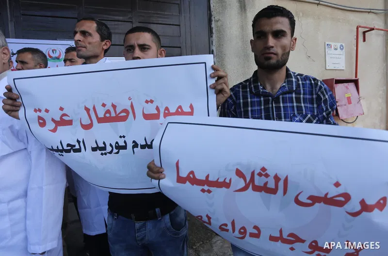 Palestinians hold banners during a protest against decision of Palestinian Authority halting shipments of baby formula and medicines to hospitals on Gaza strip, in Gaza city on May 23, 2017. Photo by Mohammed Asad