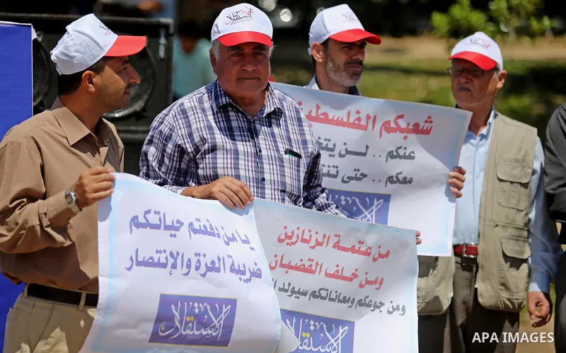 Palestinian Journalists from al-Estqlal newspaper hold placards during a protest in support of Palestinian hunger-striking prisoners held in Israeli jails, as they work on printing special edition at protest tent in Gaza...