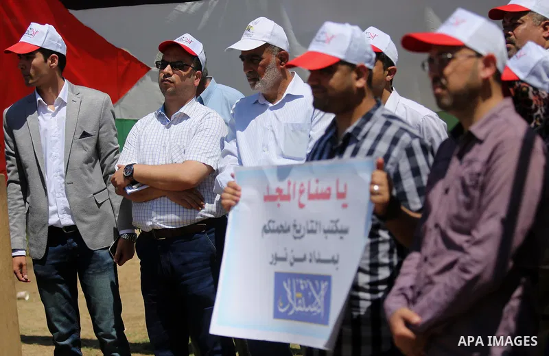 Palestinian Journalists from al-Estqlal newspaper hold placards during a protest in support of Palestinian hunger-striking prisoners held in Israeli jails, as they work on printing special edition at protest tent in Gaza...