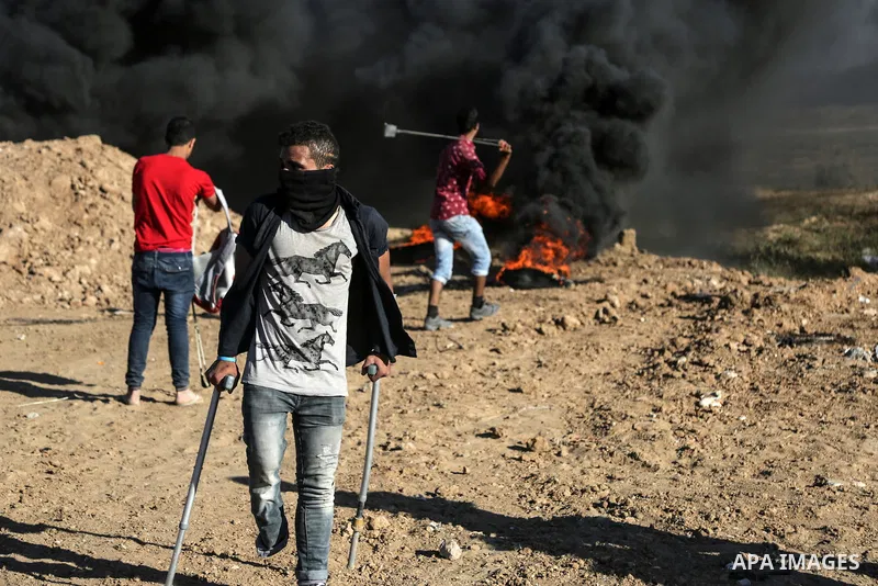 A Palestinian protester uses a slingshot to hurl stones towards Israeli security forces during clashes near the border between Israel and Central Gaza Strip May 26, 2017. Photo by Nidal Alwaheidi