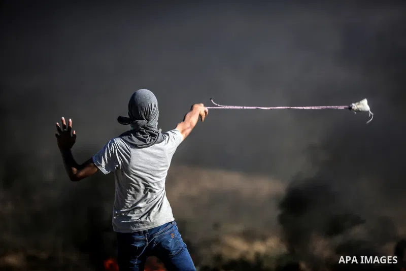 A Palestinian protester uses a slingshot to hurl stones towards Israeli security forces during clashes near the border between Israel and Central Gaza Strip May 26, 2017. Photo by Nidal Alwaheidi