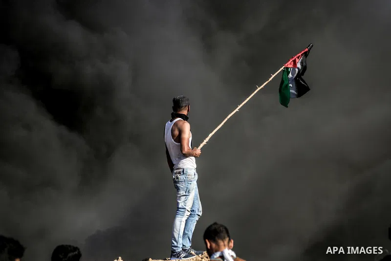 A Palestinian protester waves the national flag during clashes with Israeli security forces near the border between Israel and Central Gaza Strip May 26, 2017. Photo by Nidal Alwaheidi
