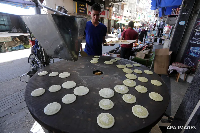 A Palestinian vendor prepares traditional pancakes known as ''Qatayef'' on the holy month of Ramadan at market in Gaza city on May 27, 2017. Ramadan is sacred to Muslims because it is during that month that tradition say...