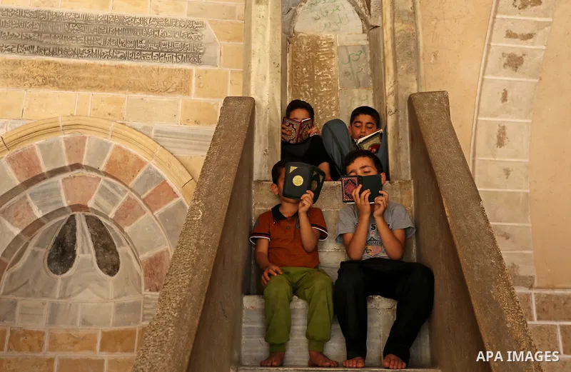 Palestinian children read copies of the Koran, Islam's holiest book, on the first day of fasting in the Muslim holy month of Ramadan, at the al-Omari mosque in Gaza City, on May 27, 2017. Ramadan is sacred to Muslims bec...