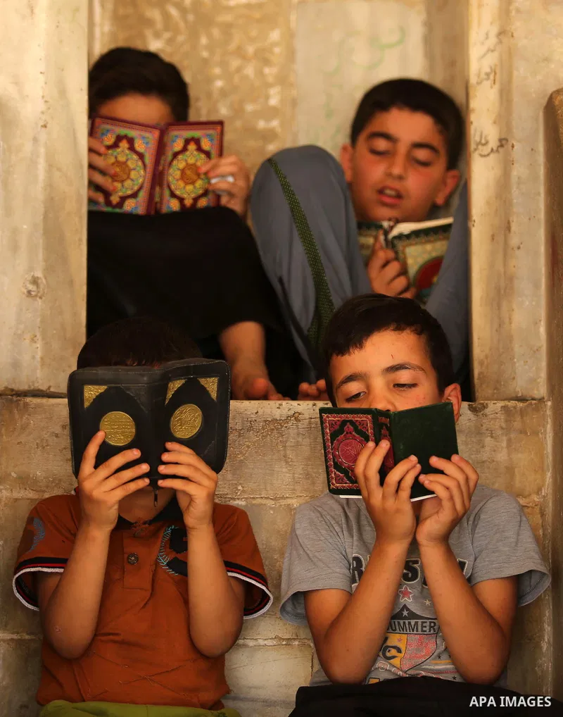 Palestinian children read copies of the Koran, Islam's holiest book, on the first day of fasting in the Muslim holy month of Ramadan, at the al-Omari mosque in Gaza City, on May 27, 2017. Ramadan is sacred to Muslims bec...