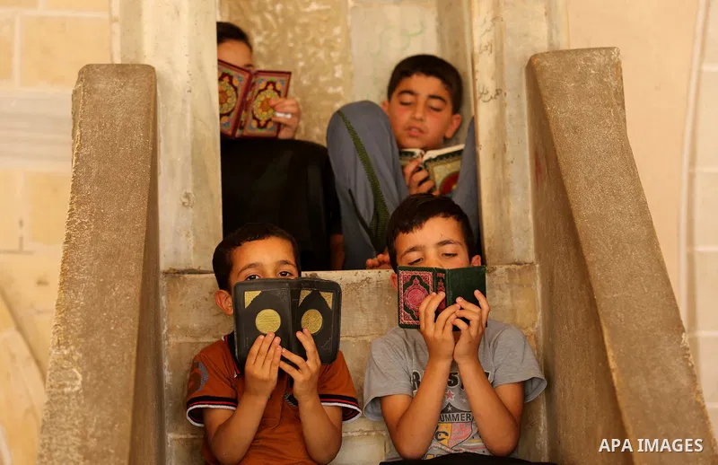 Palestinian children read copies of the Koran, Islam's holiest book, on the first day of fasting in the Muslim holy month of Ramadan, at the al-Omari mosque in Gaza City, on May 27, 2017. Ramadan is sacred to Muslims bec...