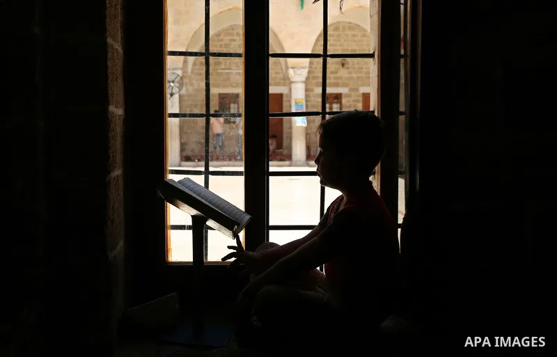 A Palestinian boy reads a copy of the Koran, Islam's holiest book, on the Muslim holy fasting month of Ramadan at the al- Sayed Hashim mosque in Gaza city on May 29, 2017. Ramadan is sacred to Muslims because it is durin...