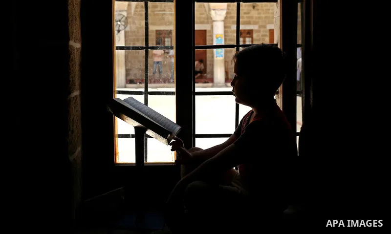 A Palestinian boy reads a copy of the Koran, Islam's holiest book, on the Muslim holy fasting month of Ramadan at the al- Sayed Hashim mosque in Gaza city on May 29, 2017. Ramadan is sacred to Muslims because it is durin...