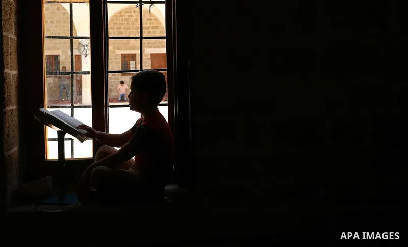 A Palestinian boy reads a copy of the Koran, Islam's holiest book, on the Muslim holy fasting month of Ramadan at the al- Sayed Hashim mosque in Gaza city on May 29, 2017. Ramadan is sacred to Muslims because it is durin...