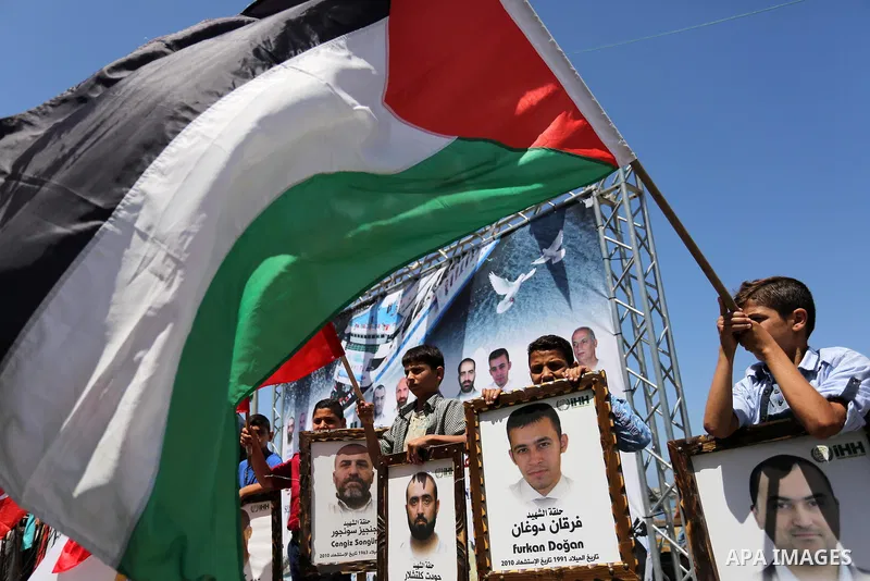 Palestinian children hold the Palestinian and Turkish flags and picture of activists who was dead by Israeli forces during a rally to mark the 7th anniversary of the Mavi Marmara Gaza flotilla incident, at the seaport of...