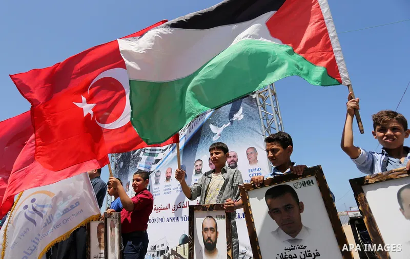 Palestinian children hold the Palestinian and Turkish flags and picture of activists who was dead by Israeli forces during a rally to mark the 7th anniversary of the Mavi Marmara Gaza flotilla incident, at the seaport of...