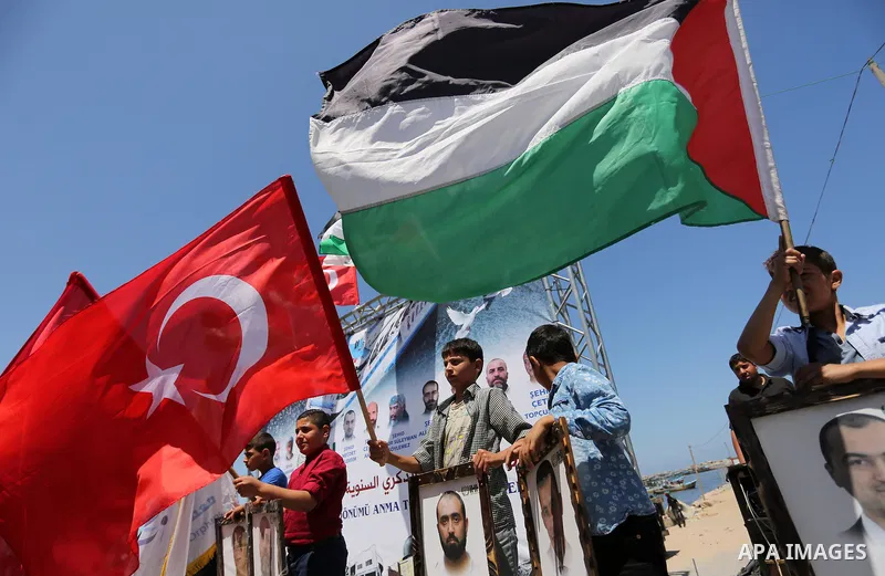 Palestinian children hold the Palestinian and Turkish flags and picture of activists who was dead by Israeli forces during a rally to mark the 7th anniversary of the Mavi Marmara Gaza flotilla incident, at the seaport of...