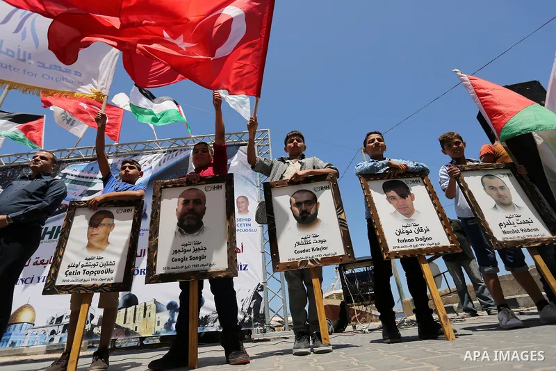Palestinian children hold the Palestinian and Turkish flags and picture of activists who was dead by Israeli forces during a rally to mark the 7th anniversary of the Mavi Marmara Gaza flotilla incident, at the seaport of...