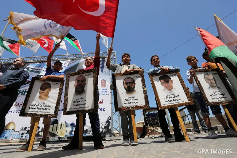 Palestinian children hold the Palestinian and Turkish flags and picture of activists who was dead by Israeli forces during a rally to mark the 7th anniversary of the Mavi Marmara Gaza flotilla incident, at the seaport of...