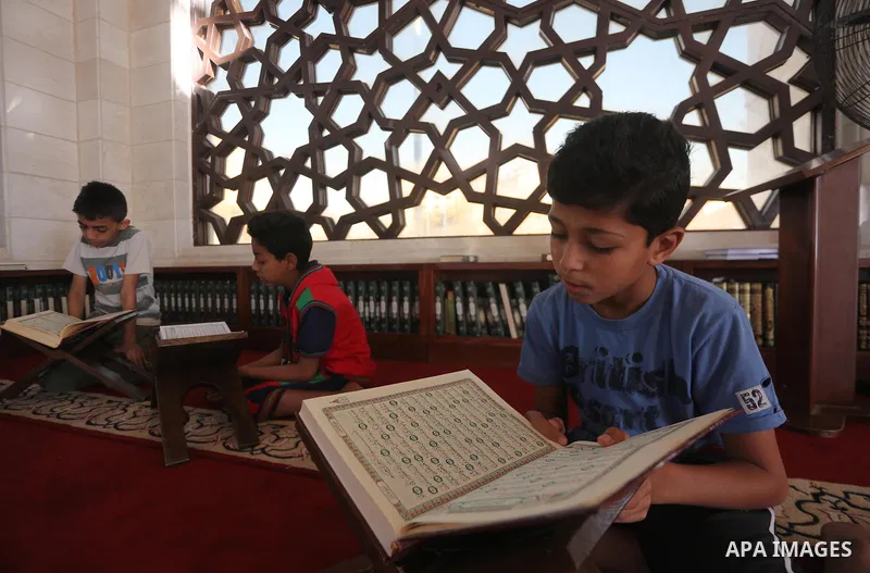 A Palestinian boy reads a copy of the Koran, Islam's holiest book, on the Muslim holy fasting month of Ramadan at al-Khaldi mosque in Gaza city on May 31, 2017. Ramadan is sacred to Muslims because it is during that mont...
