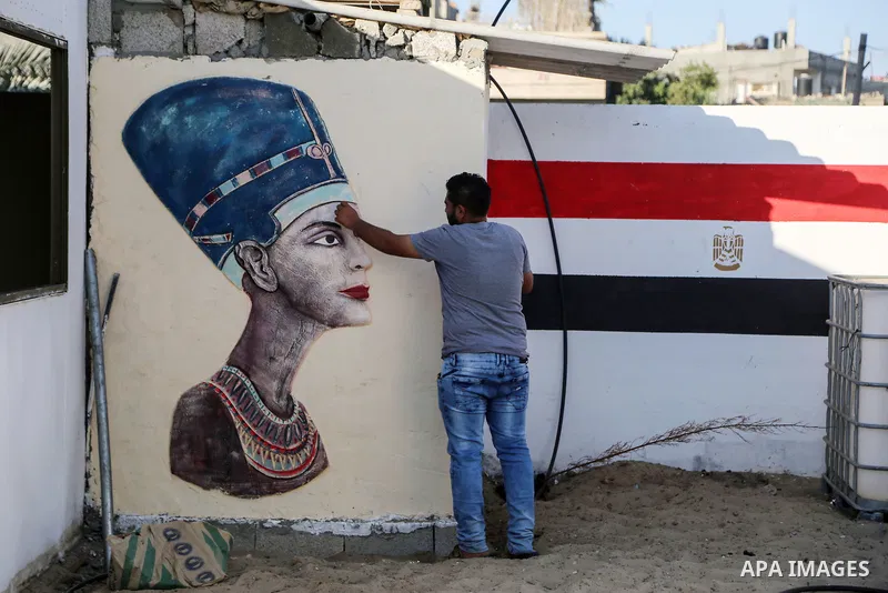 A Palestinian artist paints on a mural drawings of Pharaonic figure at a technical site in the southern Gaza Strip town of Rafah, near the border with Egypt, on June 1, 2017. Young artists Palestinian artists Nidal Al-Ja...