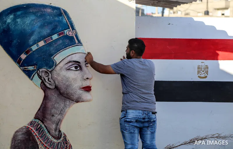 A Palestinian artist paints on a mural drawings of Pharaonic figure at a technical site in the southern Gaza Strip town of Rafah, near the border with Egypt, on June 1, 2017. Young artists Palestinian artists Nidal Al-Ja...