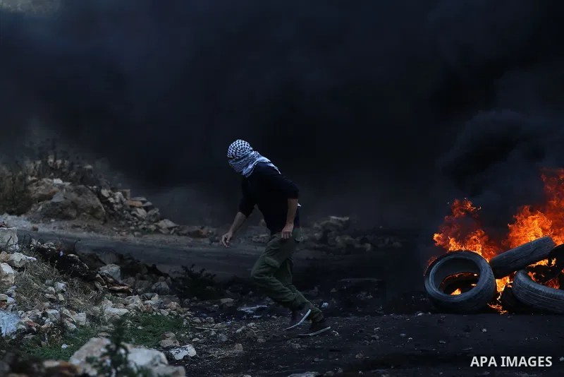 A Palestinian protester burns tires during clashes with Israeli security forces following a demonstration against the expropriation of Palestinian land by Israel in the village of Kfar Qaddum, near Nablus, in the occupie...