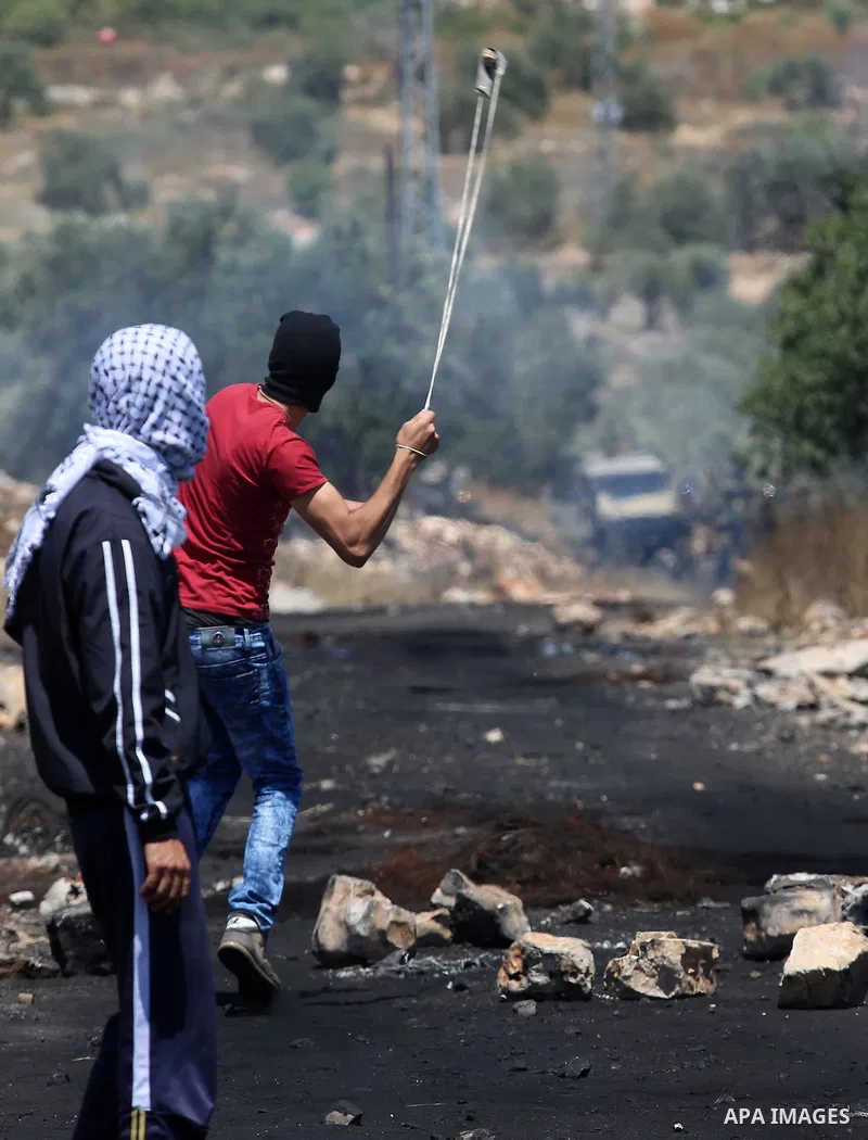 A Palestinian protester uses a slingshot to hurl stones towards Israeli security forces during clashes following a demonstration against the expropriation of Palestinian land by Israel in the village of Kfar Qaddum, near...