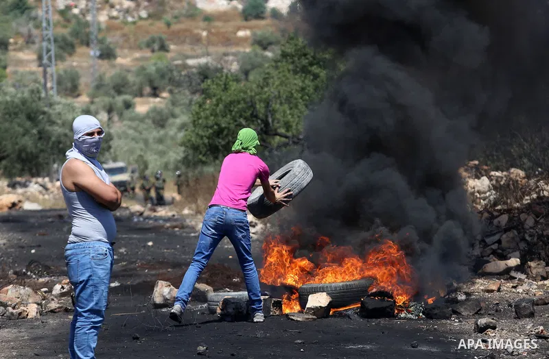 A Palestinian protester burns tires during clashes with Israeli security forces following a demonstration against the expropriation of Palestinian land by Israel in the village of Kfar Qaddum, near Nablus, in the occupie...