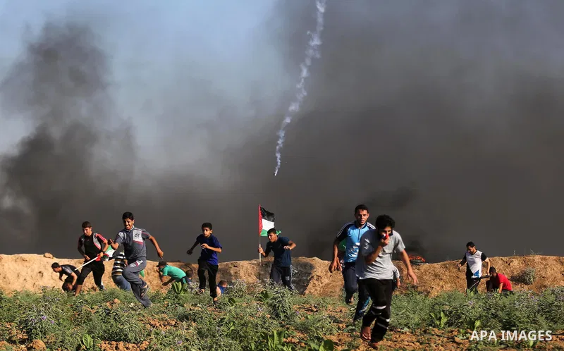 Palestinian protesters take cover during clashes with Israeli security forces following a demonstration against the blockade on the Gaza Strip, near the border fence east of Jabalia refugee camp on June 5, 2017. Photo by...