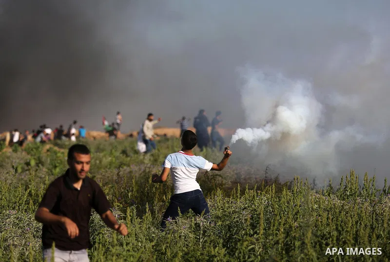 A Palestinian protester throws a tear gas canister towards Israeli security forces during clashes following a demonstration against the blockade on the Gaza Strip, near the border fence east of Jabalia refugee camp on Ju...