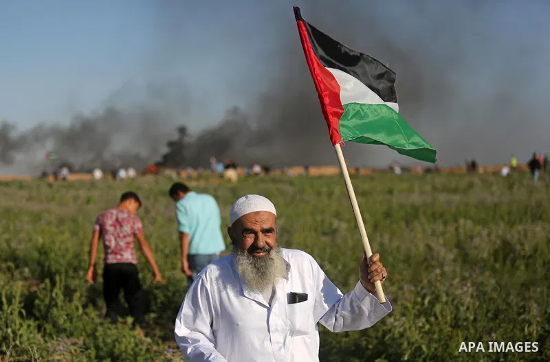 A Palestinian protester waves the national during clashes with Israeli security forces following a protest near the border fence east of Jabalia refugee camp, against the blockade on the Gaza Strip on June 5, 2017. Photo...
