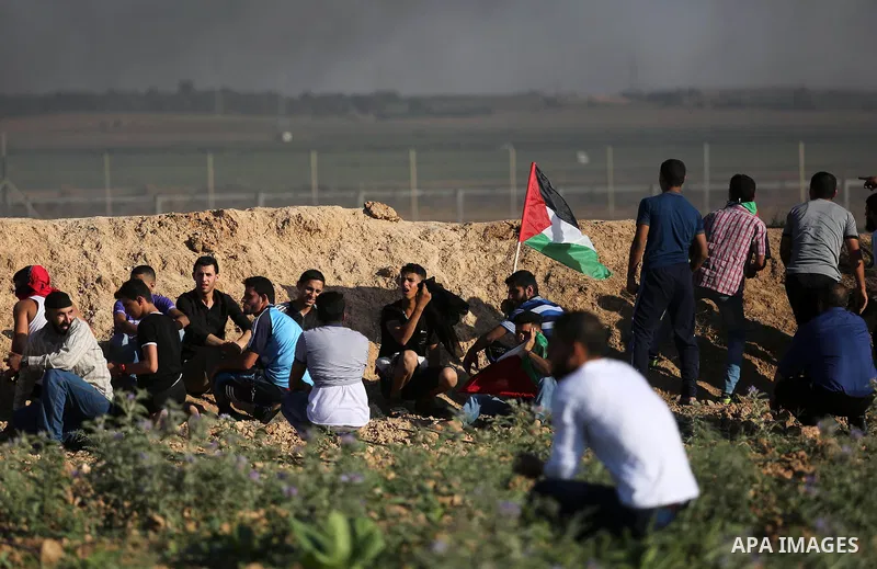 Palestinian protesters take cover during clashes with Israeli security forces following a demonstration against the blockade on the Gaza Strip, near the border fence east of Jabalia refugee camp on June 5, 2017. Photo by...