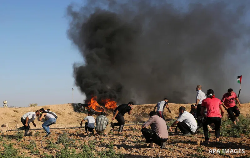 Palestinian protesters take cover during clashes with Israeli security forces following a demonstration against the blockade on the Gaza Strip, near the border fence east of Jabalia refugee camp on June 5, 2017. Photo by...
