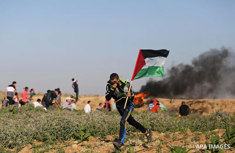 Palestinian protesters take cover during clashes with Israeli security forces following a demonstration against the blockade on the Gaza Strip, near the border fence east of Jabalia refugee camp on June 5, 2017. Photo by...