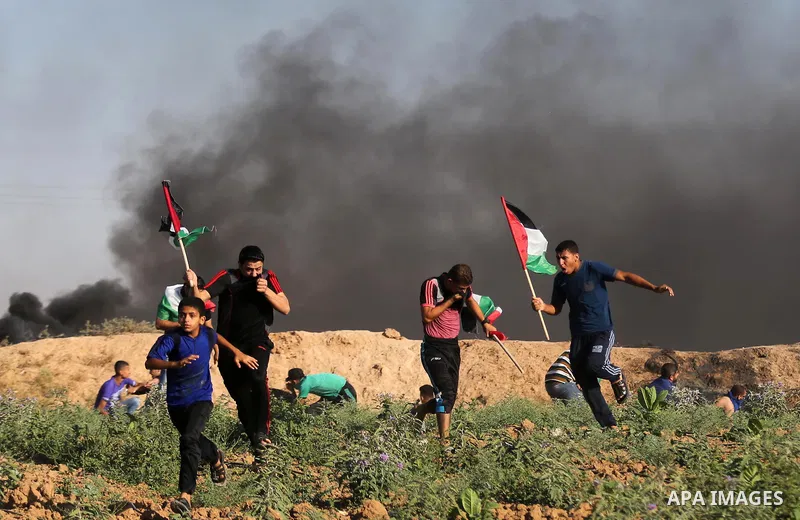 Palestinian protesters take cover during clashes with Israeli security forces following a demonstration against the blockade on the Gaza Strip, near the border fence east of Jabalia refugee camp on June 5, 2017. Photo by...