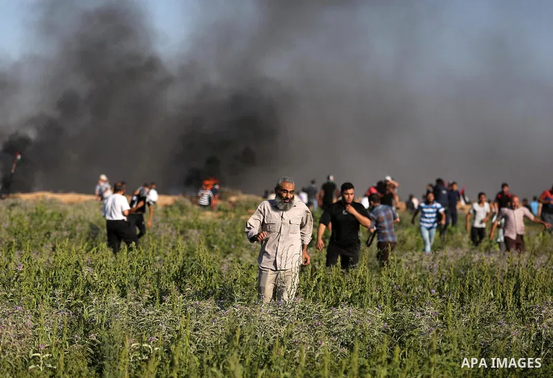 Palestinian protesters take cover during clashes with Israeli security forces following a demonstration against the blockade on the Gaza Strip, near the border fence east of Jabalia refugee camp on June 5, 2017. Photo by...