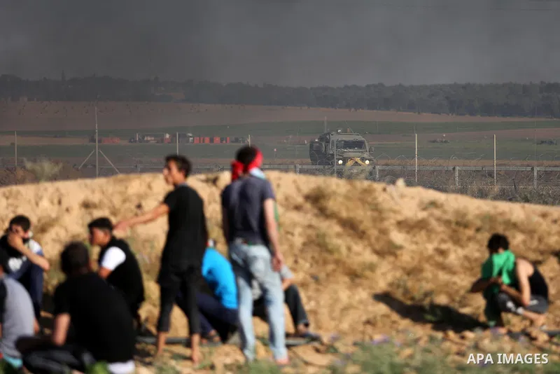 Palestinian protesters take cover during clashes with Israeli security forces following a demonstration against the blockade on the Gaza Strip, near the border fence east of Jabalia refugee camp on June 5, 2017. Photo by...