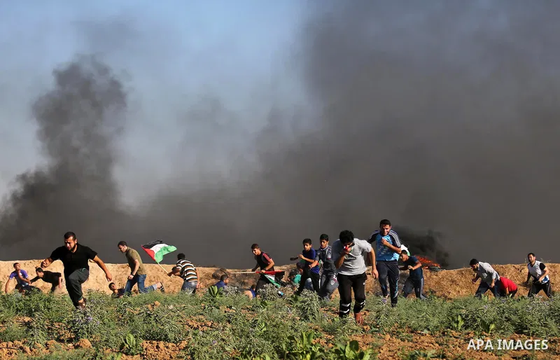 Palestinian protesters take cover during clashes with Israeli security forces following a demonstration against the blockade on the Gaza Strip, near the border fence east of Jabalia refugee camp on June 5, 2017. Photo by...