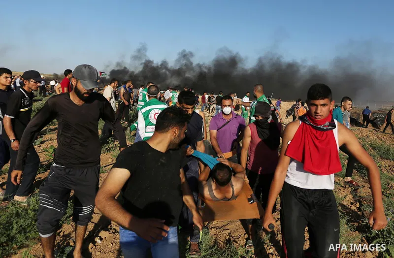 Palestinian protesters carry a wounded man during clashes with Israeli security forces following a demonstration against the blockade on the Gaza Strip, near the border fence east of Jabalia refugee camp on June 5, 2017....