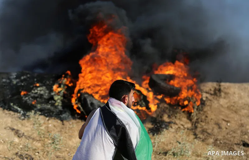 A Palestinian protester takes cover during clashes with Israeli security forces following a demonstration against the blockade on the Gaza Strip, near the border fence east of Jabalia refugee camp on June 5, 2017. Photo...