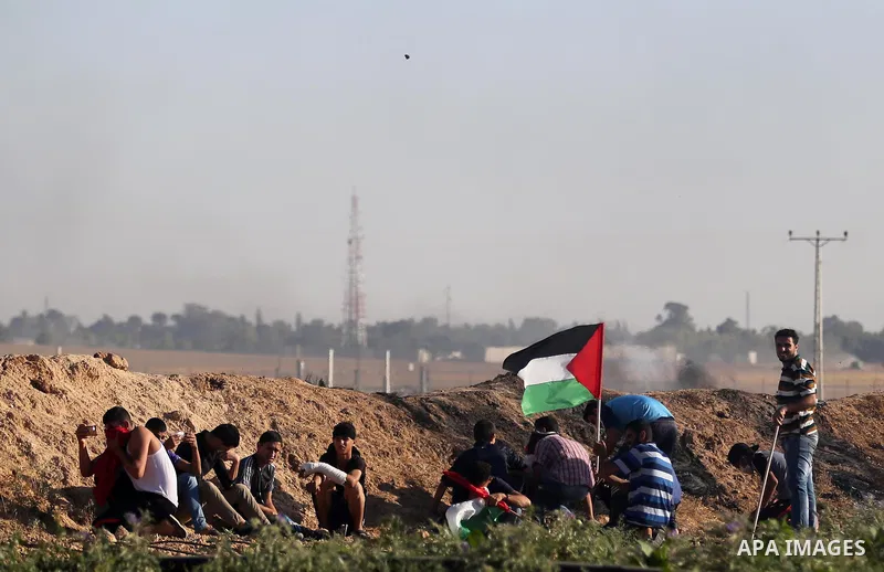 Palestinian protesters take cover during clashes with Israeli security forces following a demonstration against the blockade on the Gaza Strip, near the border fence east of Jabalia refugee camp on June 5, 2017. Photo by...