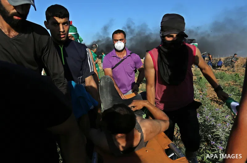 Palestinian protesters carry a wounded man during clashes with Israeli security forces following a demonstration against the blockade on the Gaza Strip, near the border fence east of Jabalia refugee camp on June 5, 2017....