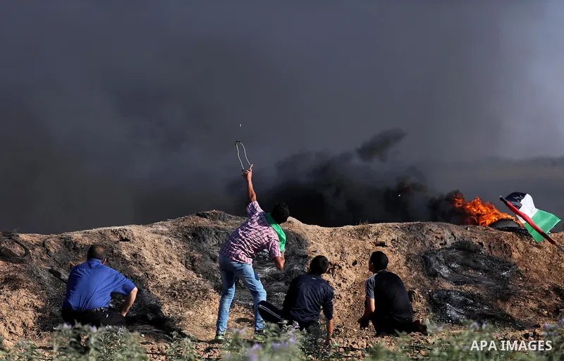 A Palestinian protester uses a slingshot to hurl stones towards Israeli security forces during clashes following a demonstration against the blockade on the Gaza Strip, near the border fence east of Jabalia refugee camp...