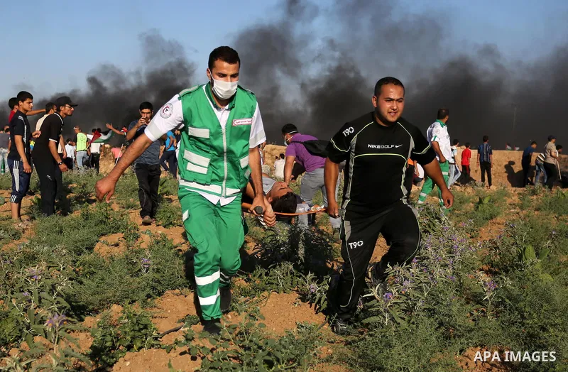 Palestinian protesters carry a wounded man during clashes with Israeli security forces following a demonstration against the blockade on the Gaza Strip, near the border fence east of Jabalia refugee camp on June 5, 2017....
