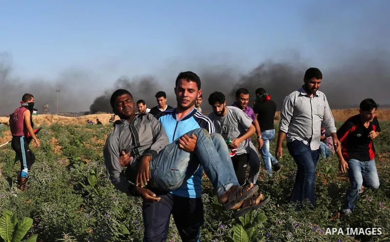 A Palestinian protester carries a wounded man during clashes with Israeli security forces following a demonstration against the blockade on the Gaza Strip, near the border fence east of Jabalia refugee camp on June 5, 20...