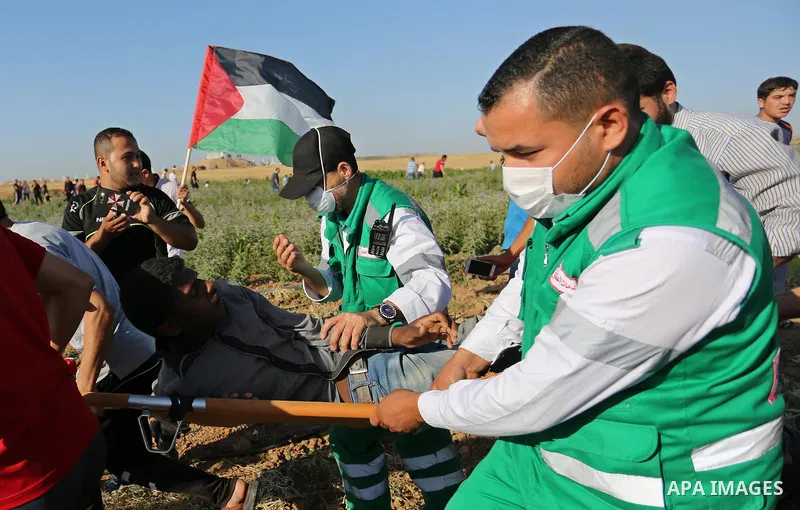 Palestinian protesters carry a wounded man during clashes with Israeli security forces following a demonstration against the blockade on the Gaza Strip, near the border fence east of Jabalia refugee camp on June 5, 2017....