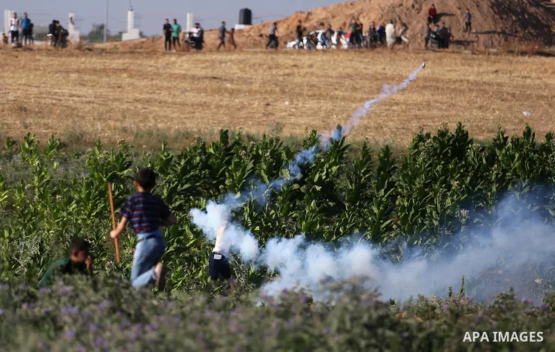 A Palestinian protester takes cover during clashes with Israeli security forces following a demonstration against the blockade on the Gaza Strip, near the border fence east of Jabalia refugee camp on June 5, 2017. Photo...