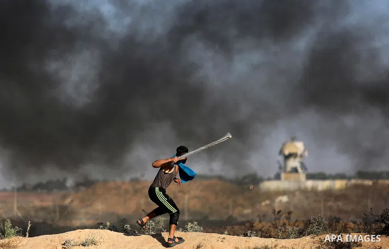 A Palestinian protester uses a slingshot to hurl stones towards Israeli security forces during clashes following a demonstration against the blockade on the Gaza Strip, near the border fence east of Jabalia refugee camp...