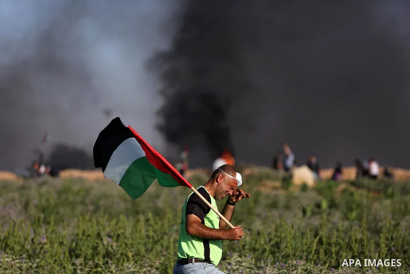 A Palestinian protester waves the national during clashes with Israeli security forces following a protest near the border fence east of Jabalia refugee camp, against the blockade on the Gaza Strip on June 5, 2017. Photo...