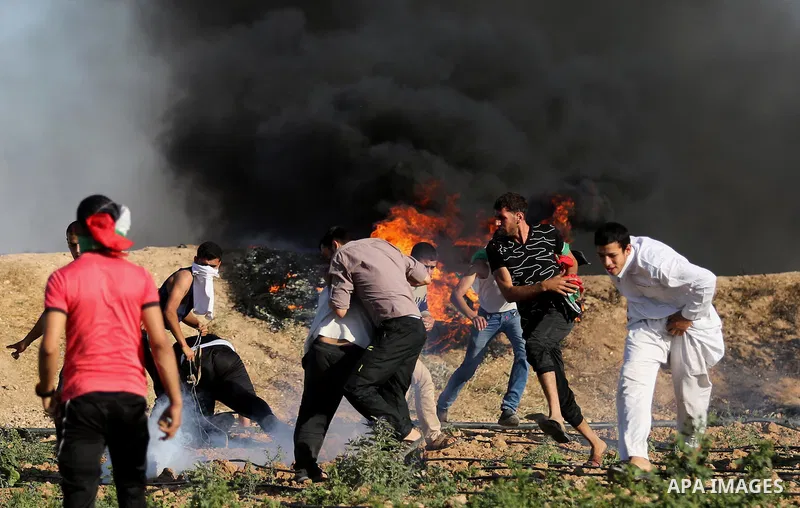 Palestinian protesters take cover during clashes with Israeli security forces following a demonstration against the blockade on the Gaza Strip, near the border fence east of Jabalia refugee camp on June 5, 2017. Photo by...