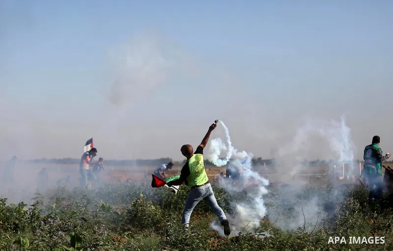 A Palestinian protester throws a tear gas canister towards Israeli security forces during clashes following a demonstration against the blockade on the Gaza Strip, near the border fence east of Jabalia refugee camp on Ju...