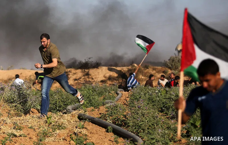 Palestinian protesters take cover during clashes with Israeli security forces following a demonstration against the blockade on the Gaza Strip, near the border fence east of Jabalia refugee camp on June 5, 2017. Photo by...