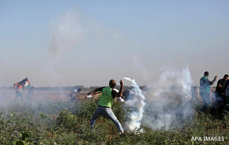 A Palestinian protester throws a tear gas canister towards Israeli security forces during clashes following a demonstration against the blockade on the Gaza Strip, near the border fence east of Jabalia refugee camp on Ju...